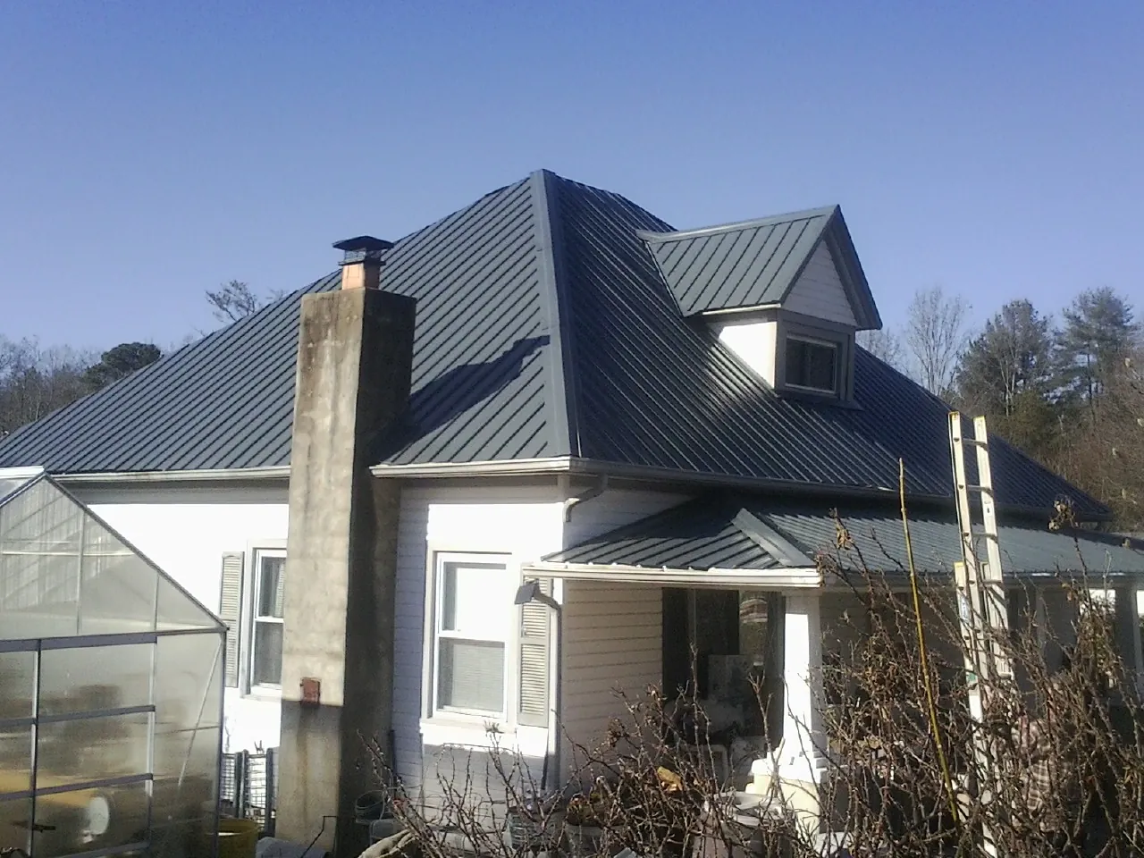 Dark blue standing seam metal roof on a white farmhouse with dormer — Slate & Tile Roof Repair by Roofing Brothers in Laveen