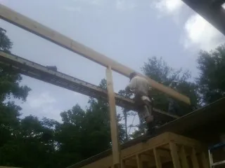 Carpenter setting a ridge beam over a new addition frame — Ice Dam Removal by Roofing Brothers in Laveen