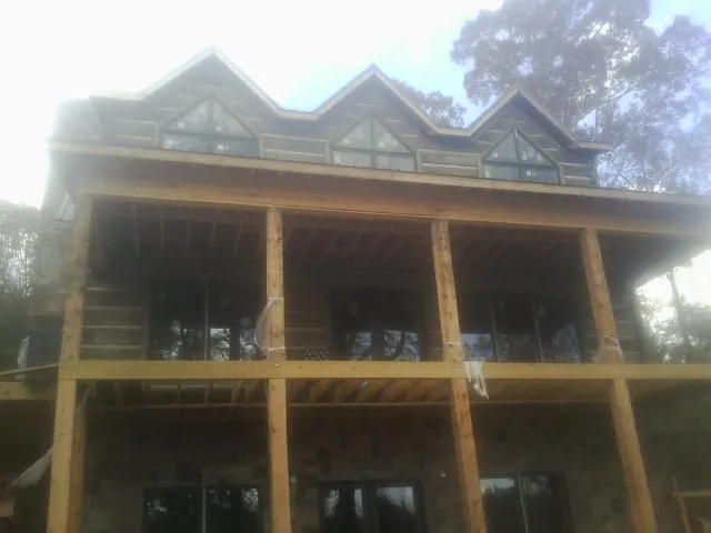 Dormers and porch framing on a large log home under construction — Roof Coating work by our crew in Laveen