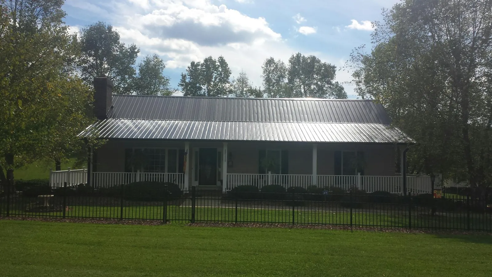 Gray metal roof on a brick ranch with a full width front porch — Gutter Guard Installation work by our crew in Laveen