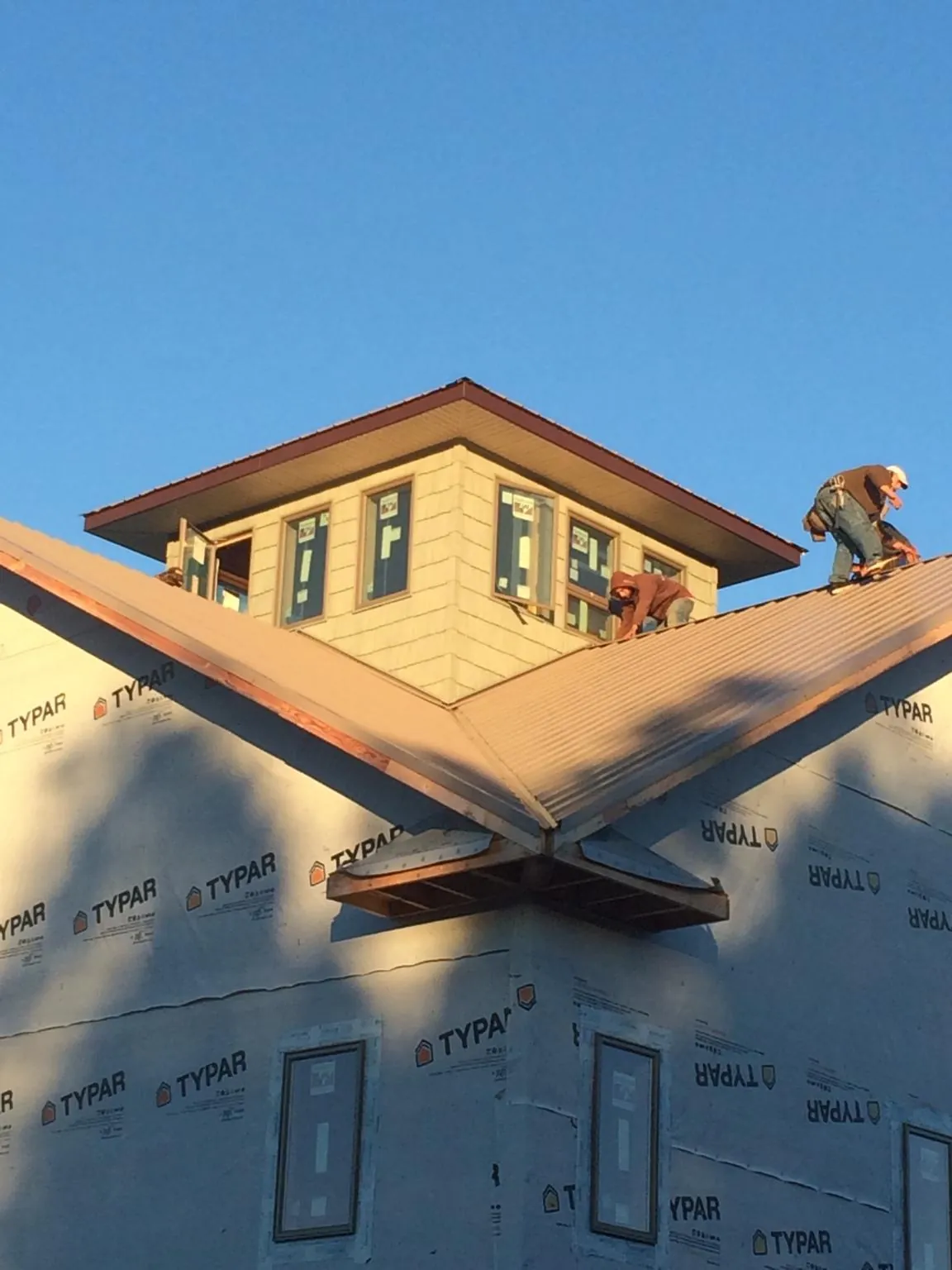 Roofers working around a rooftop cupola on a new metal roof at sunset — Roof Waterproofing in Laveen by Roofing Brothers